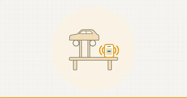 A workshop bench with a ringing phone on it, a raised car behind.